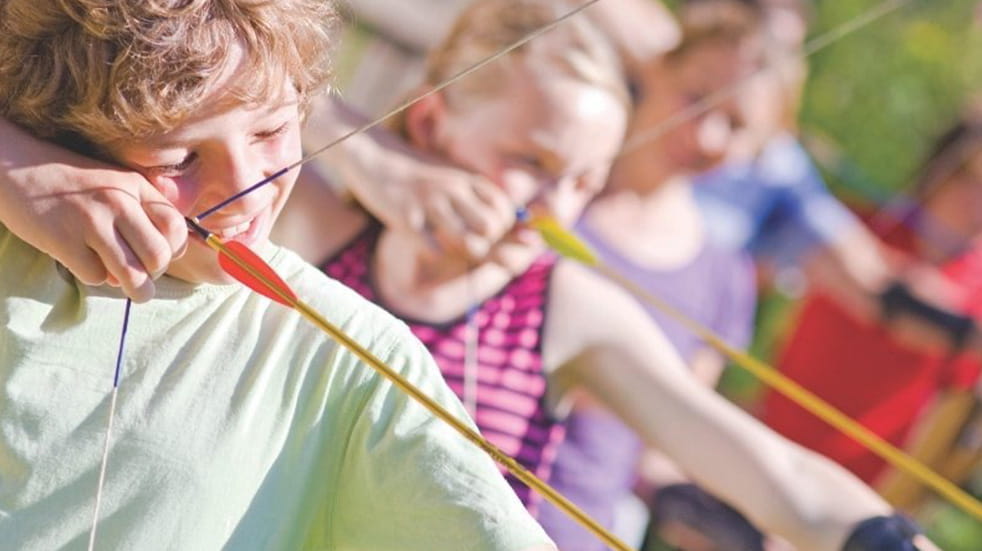 Close up of children doing archery, pulling back the string of their bow at Whitemead Forest Park